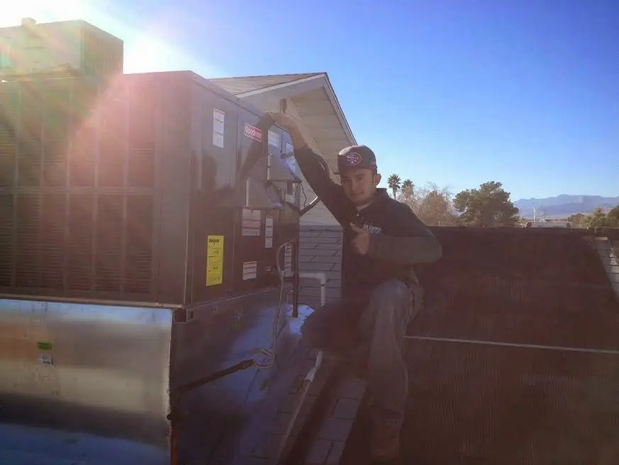 HVAC technician performing Air Duct Cleaning on a rooftop unit in Ione